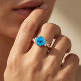 Anillo de compromiso de oro con tres diamantes y topacio azul suizo redondo